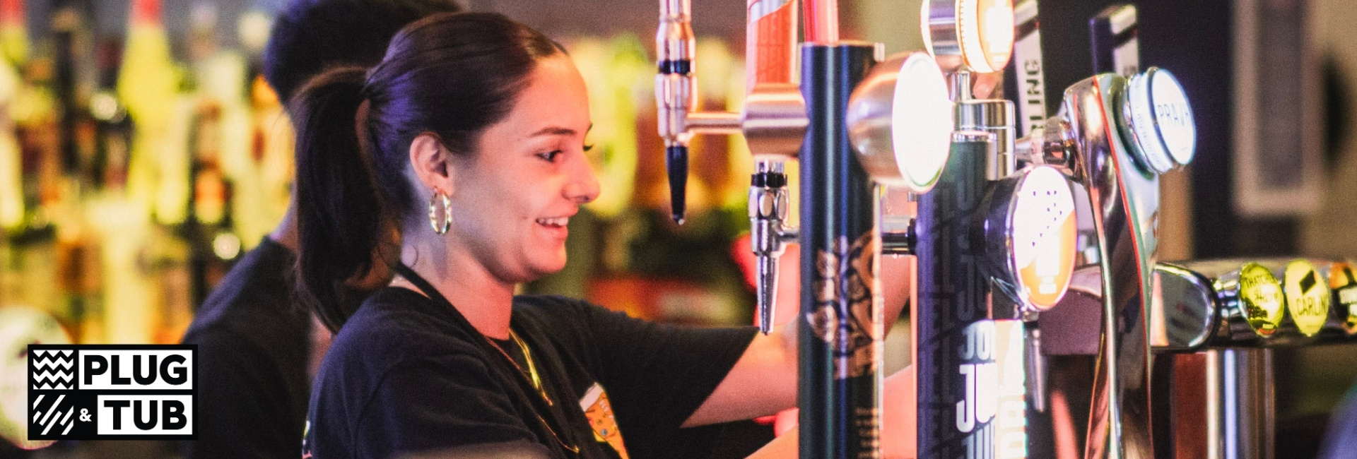 women pulling pints behind bar