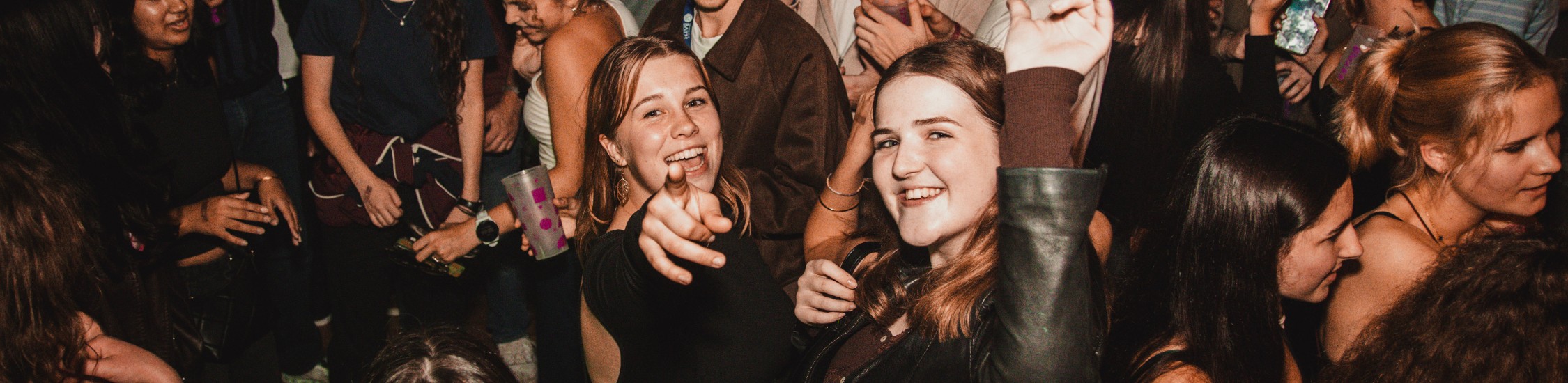 two student girls pointing at camera in club