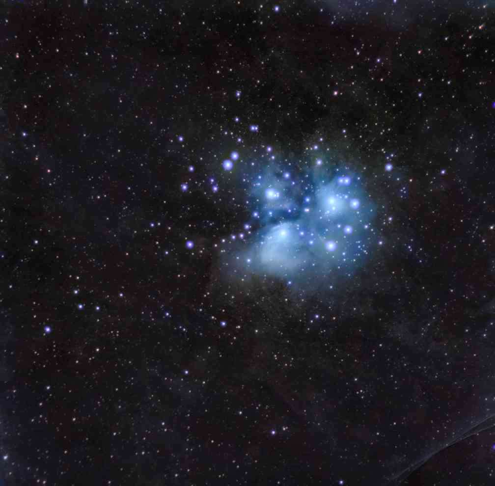 Pleiadies star cluster with surrounding nebula in cool blue colours.