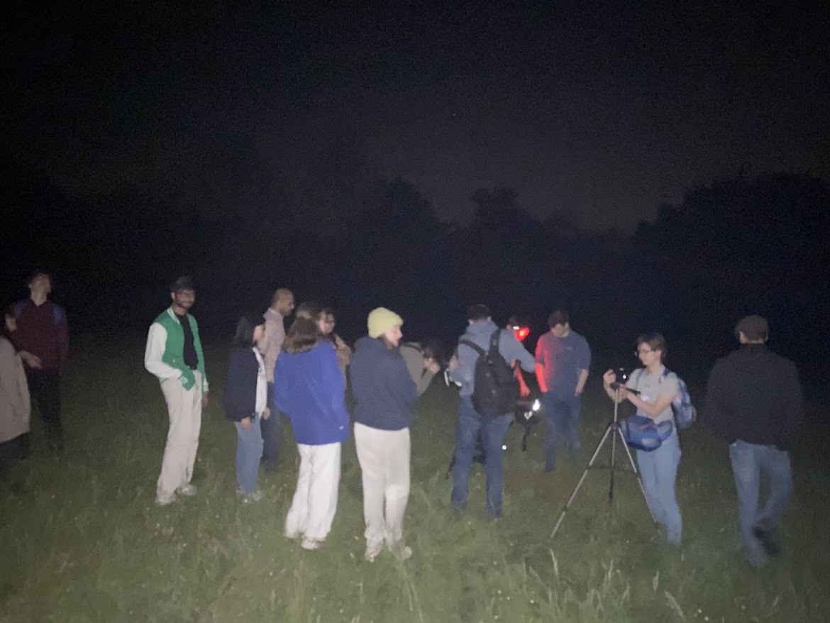 A crowd of students are looking for aurora. Some students have cameras and torches.
